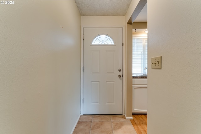 doorway to outside featuring a sink, baseboards, and a textured ceiling