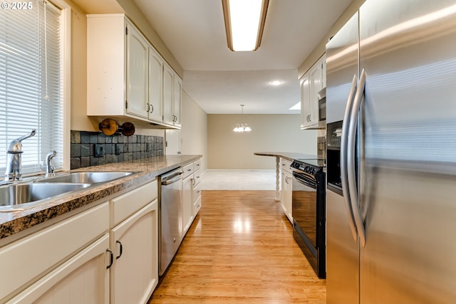 kitchen with white cabinets, light wood-style floors, appliances with stainless steel finishes, and a sink