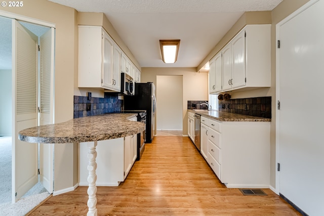 kitchen with visible vents, a sink, white cabinets, appliances with stainless steel finishes, and light wood-type flooring