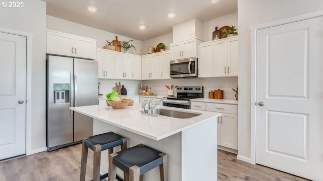 3422 SW Hartley Ave, Gresham, OR 97080 - kitchen with appliances with stainless steel finishes, light wood finished floors, white cabinets, an island with sink, and a kitchen bar