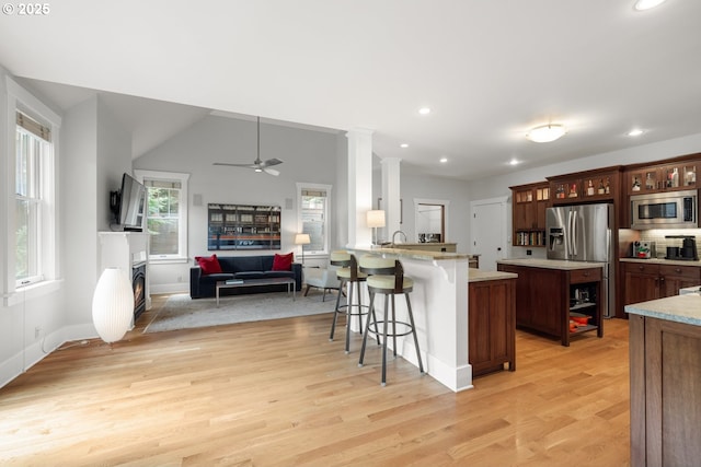 12624 SW 22nd Ave, Lake Oswego, OR 97034 - kitchen with appliances with stainless steel finishes, a peninsula, a kitchen breakfast bar, open floor plan, and light wood-style flooring