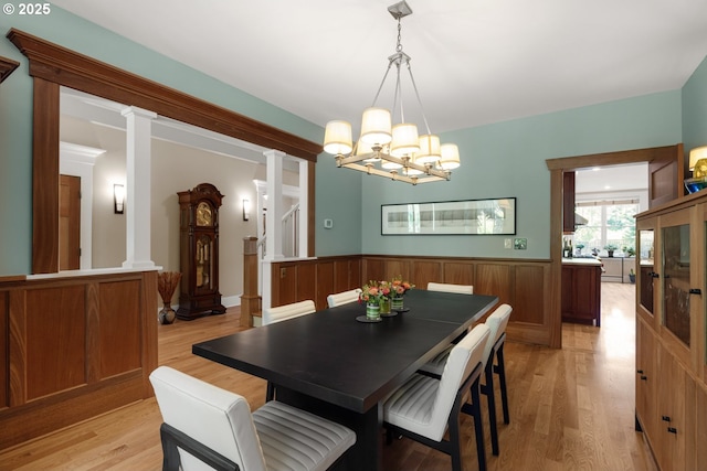 12624 SW 22nd Ave, Lake Oswego, OR 97034 - dining room with a chandelier, light wood-style flooring, a wainscoted wall, and decorative columns