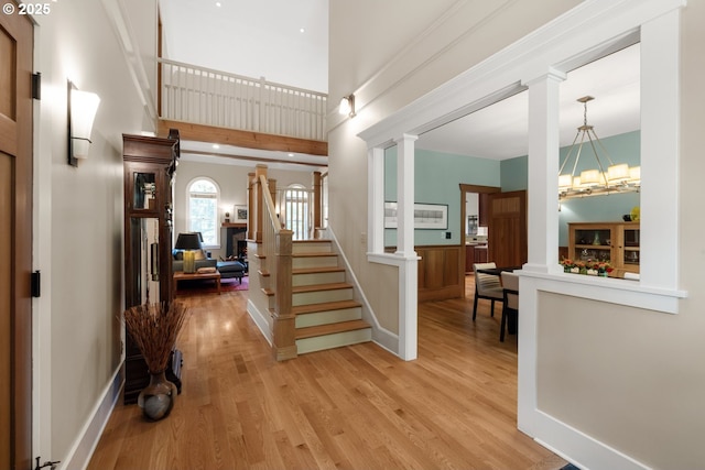 12624 SW 22nd Ave, Lake Oswego, OR 97034 - foyer featuring decorative columns, light wood-style flooring, stairs, a towering ceiling, and a chandelier