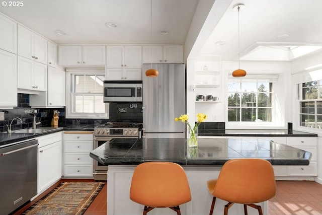 kitchen featuring stainless steel appliances, a kitchen bar, and a healthy amount of sunlight