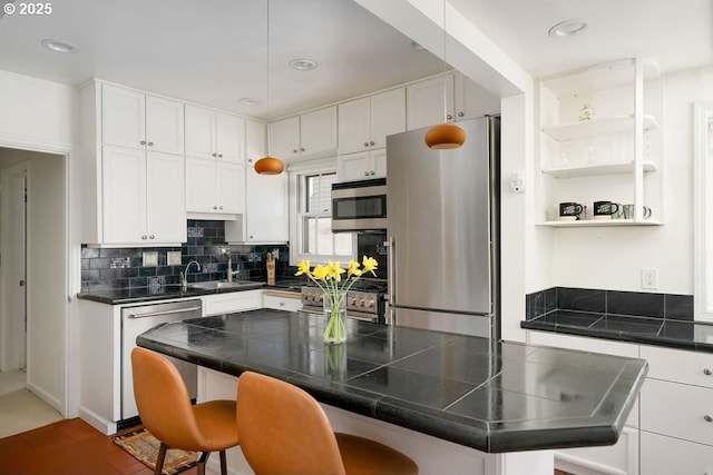 kitchen featuring white cabinets, a center island, backsplash, a breakfast bar, and appliances with stainless steel finishes