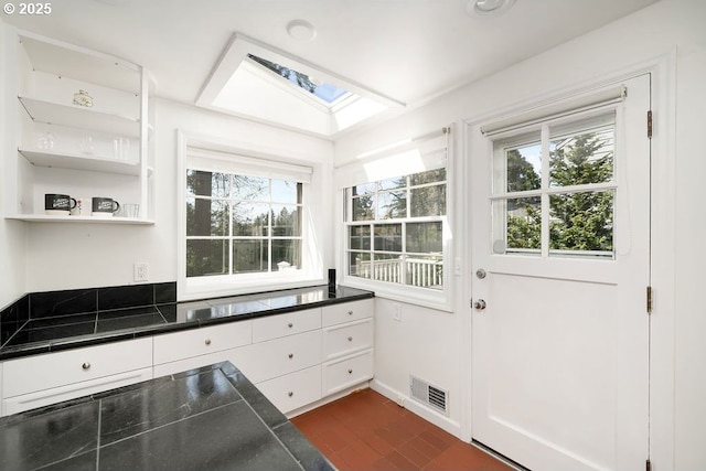 kitchen with visible vents, white cabinetry, a skylight, open shelves, and dark wood-type flooring