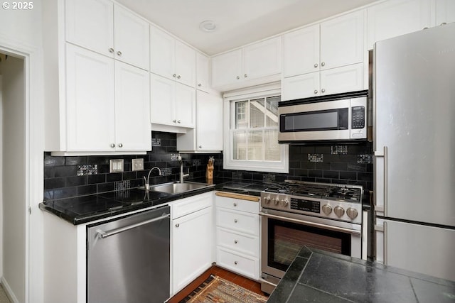 kitchen featuring a sink, dark countertops, white cabinetry, decorative backsplash, and appliances with stainless steel finishes