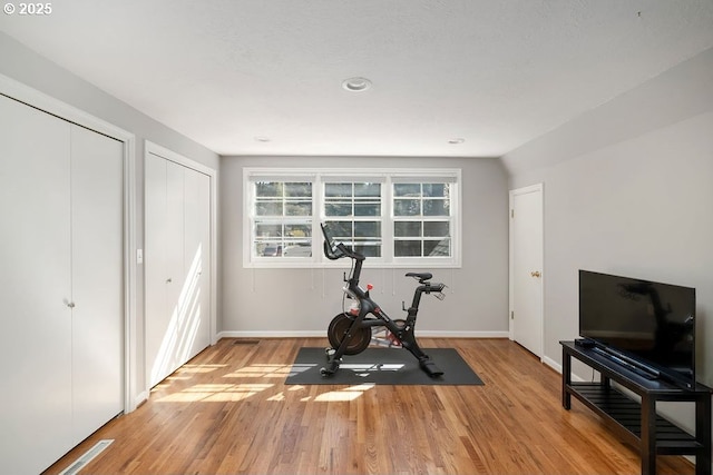 exercise area with baseboards and light wood-style floors