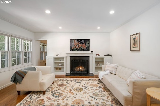 living area featuring recessed lighting, wood finished floors, a lit fireplace, and ornamental molding