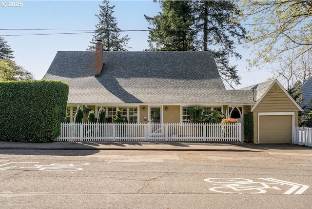 farmhouse-style home featuring a fenced front yard, a chimney, concrete driveway, a shingled roof, and an attached garage
