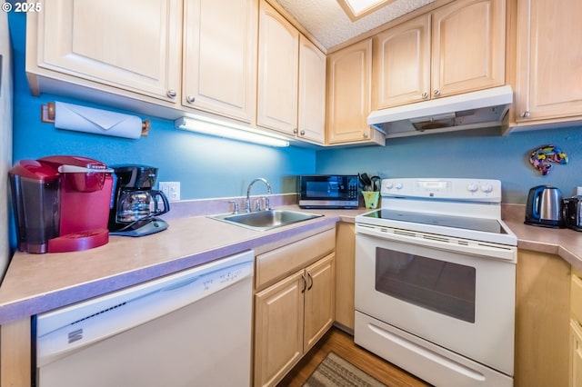 kitchen featuring white appliances, under cabinet range hood, a sink, and light countertops