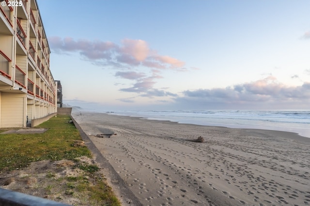 view of asphalt road featuring view of water and beach