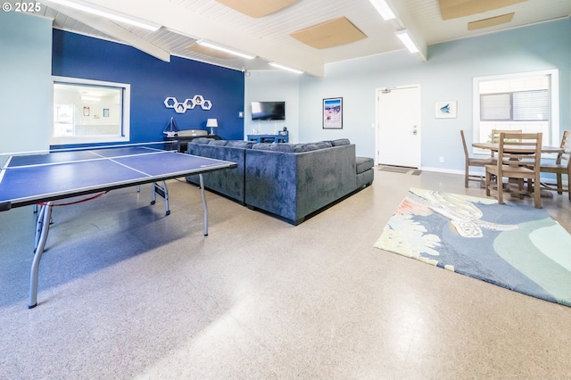 rec room with beam ceiling, speckled floor, and baseboards