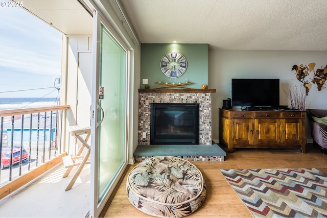 living room featuring a textured ceiling, a fireplace, and wood finished floors