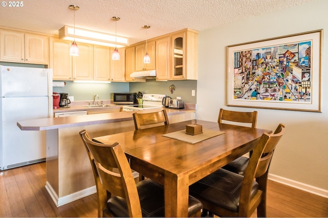 dining space featuring dark wood finished floors, a textured ceiling, and baseboards
