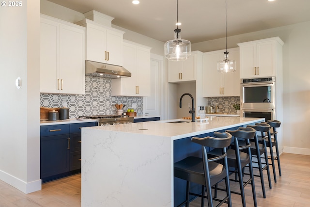 15174 SW 164th Ave Unit L12, Tigard, OR 97224 - kitchen with under cabinet range hood, stainless steel appliances, baseboards, backsplash, and a sink