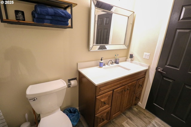 bathroom with toilet, vanity, and hardwood / wood-style floors