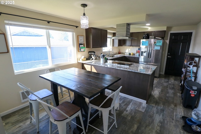 kitchen with stainless steel refrigerator with ice dispenser, ventilation hood, dark brown cabinetry, and decorative light fixtures