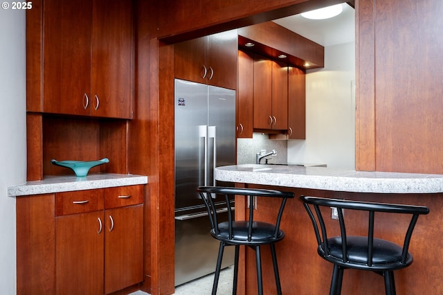 kitchen with a peninsula, a kitchen bar, decorative backsplash, and a sink