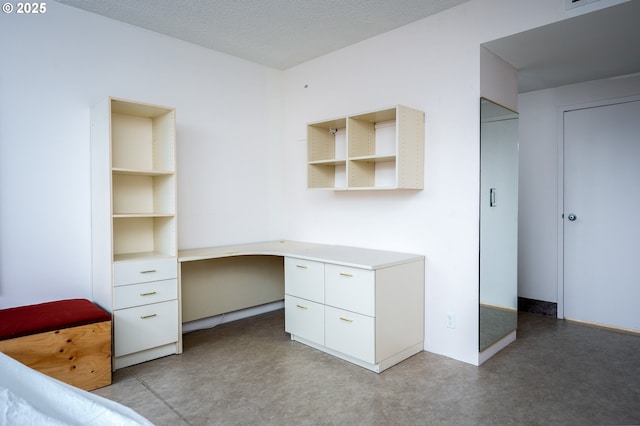 unfurnished office featuring a textured ceiling, concrete flooring, and built in study area