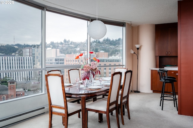 dining room featuring a view of city, a baseboard heating unit, light carpet, a textured ceiling, and a wall of windows