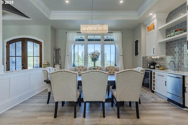 dining area with french doors, beverage cooler, an inviting chandelier, a raised ceiling, and light hardwood / wood-style floors