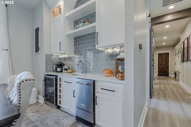 kitchen featuring white cabinetry, sink, wine cooler, and tasteful backsplash