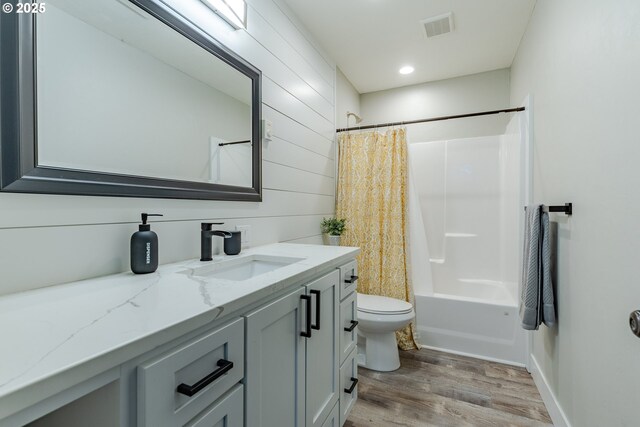 full bathroom with hardwood / wood-style flooring, vanity, shower / bath combination with curtain, and toilet