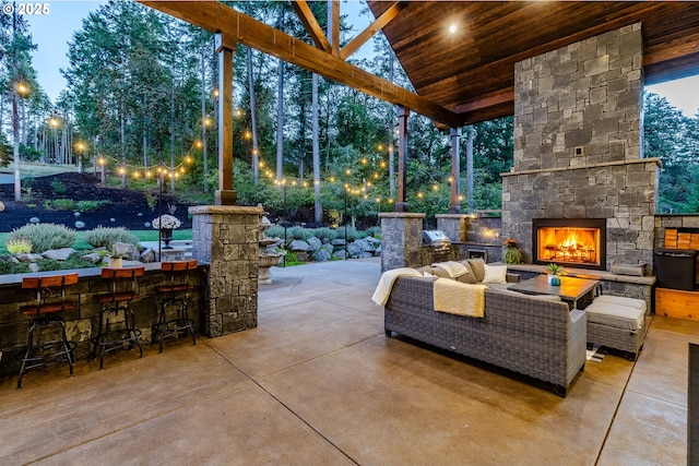 view of patio featuring grilling area, an outdoor bar, and an outdoor stone fireplace