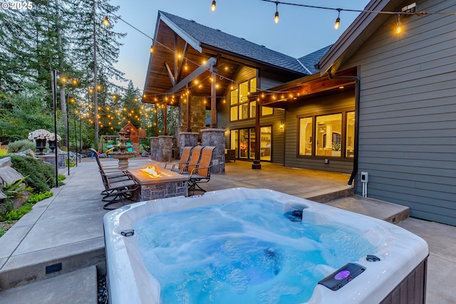 patio terrace at dusk featuring a hot tub and a fire pit