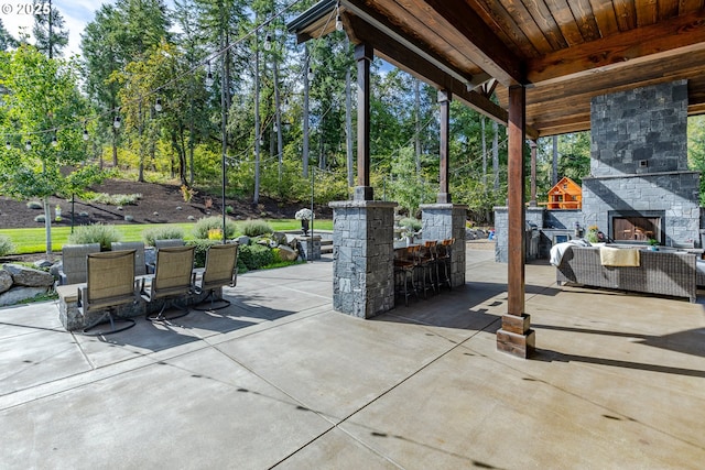 view of patio / terrace with a bar and an outdoor stone fireplace