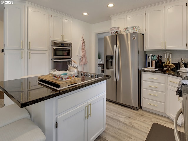 kitchen featuring appliances with stainless steel finishes, light hardwood / wood-style flooring, and white cabinetry