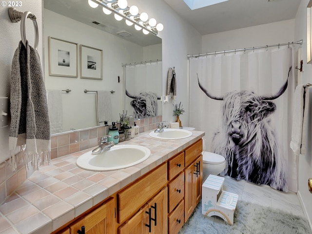 bathroom featuring vanity, toilet, and a skylight