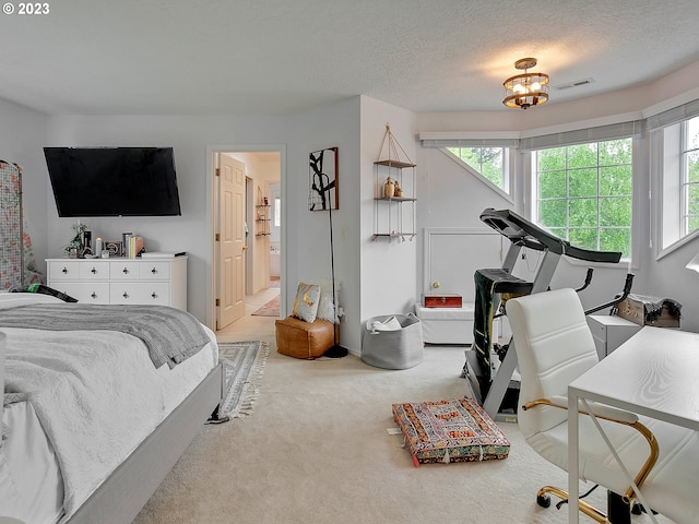 bedroom featuring carpet, a chandelier, a textured ceiling, and ensuite bath