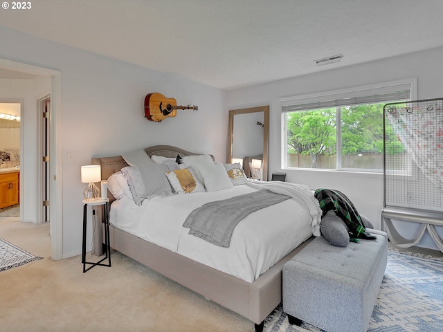 bedroom with connected bathroom and light carpet