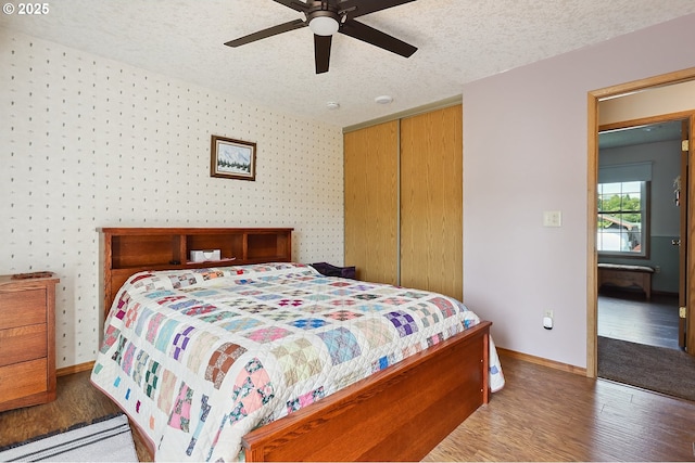620 Sherman Dr, The Dalles, OR 97058 - bedroom featuring wood finished floors, a closet, wallpapered walls, a textured ceiling, and ceiling fan