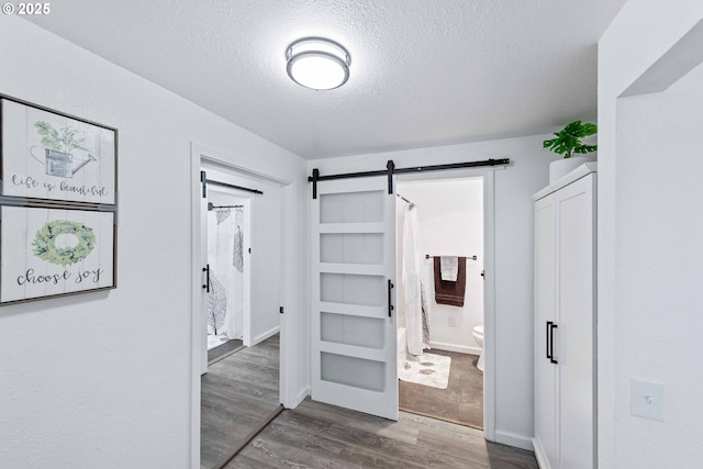 586 11th Ave, Coos Bay, OR 97420 - unfurnished bedroom featuring wood finished floors, a textured ceiling, a barn door, and connected bathroom