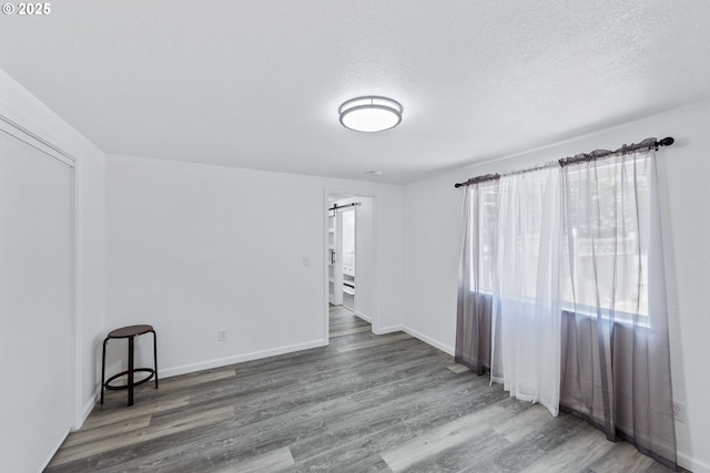 586 11th Ave, Coos Bay, OR 97420 - empty room featuring a barn door, wood finished floors, a textured ceiling, and baseboards
