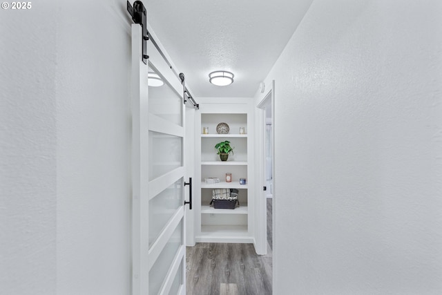 586 11th Ave, Coos Bay, OR 97420 - corridor with a barn door, wood finished floors, a textured ceiling, built in features, and a textured wall