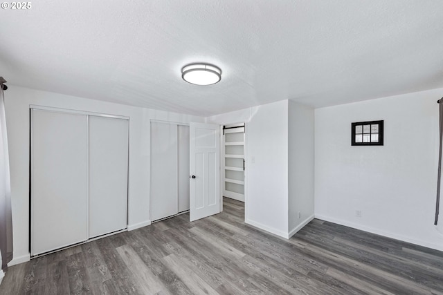 586 11th Ave, Coos Bay, OR 97420 - unfurnished bedroom with wood finished floors, a textured ceiling, baseboards, and multiple closets