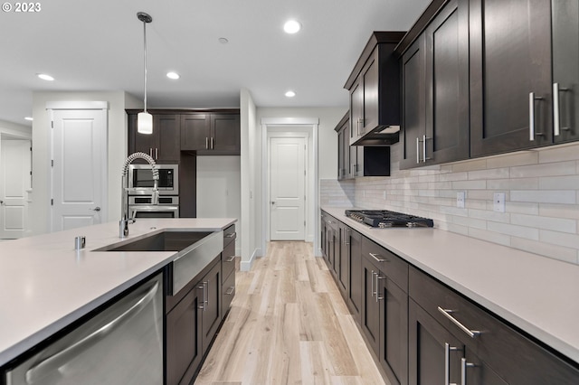 kitchen featuring stainless steel appliances, tasteful backsplash, light countertops, and under cabinet range hood