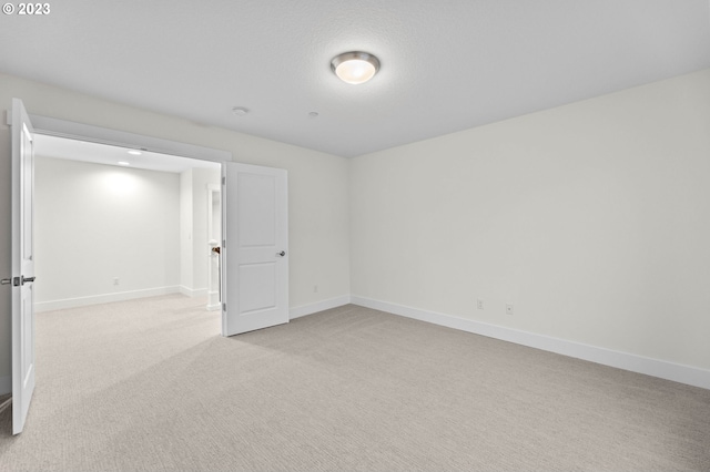 spare room with light colored carpet and baseboards