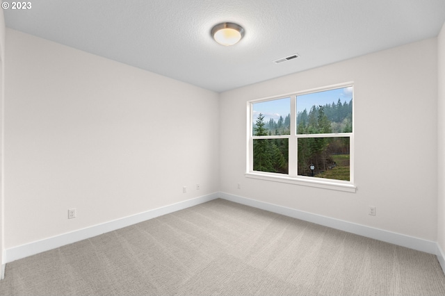 spare room with carpet, visible vents, a textured ceiling, and baseboards