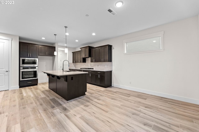 kitchen featuring visible vents, decorative backsplash, appliances with stainless steel finishes, light countertops, and light wood-style floors