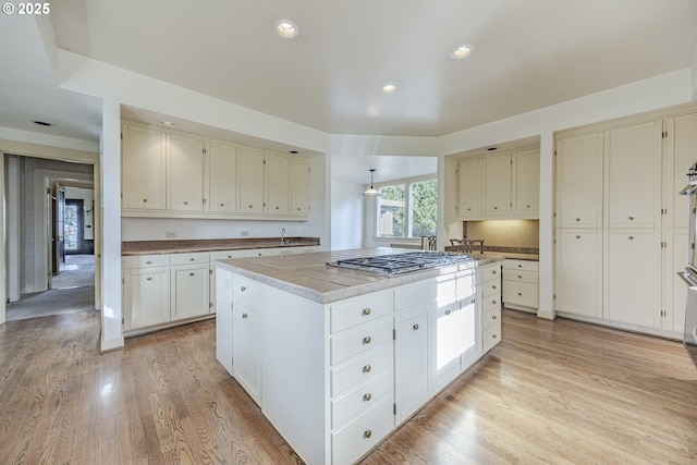 kitchen featuring light hardwood / wood-style flooring, a center island, white cabinets, and stainless steel gas cooktop