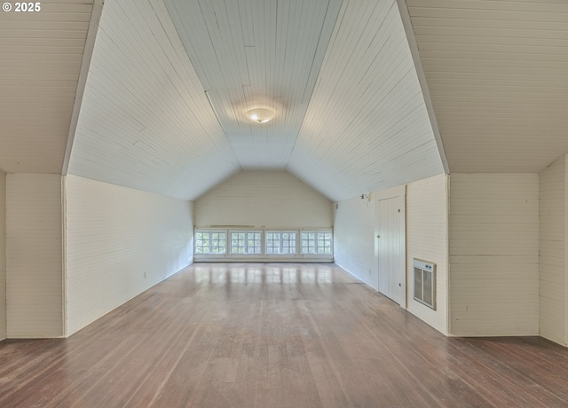 additional living space featuring lofted ceiling, hardwood / wood-style flooring, and heating unit