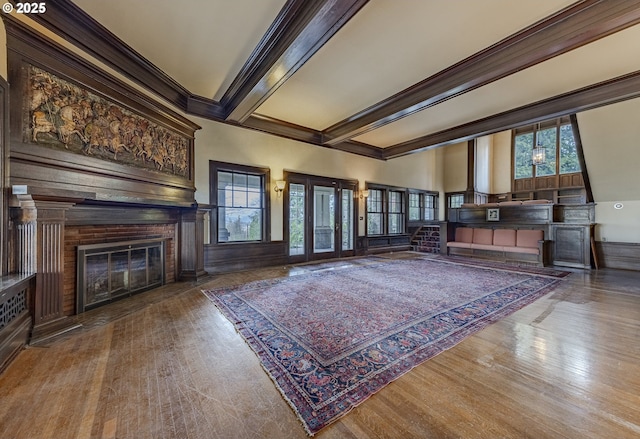 unfurnished living room with a wealth of natural light, hardwood / wood-style floors, and beam ceiling