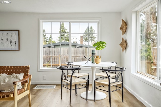 dining area featuring a healthy amount of sunlight, light wood-type flooring, and baseboards