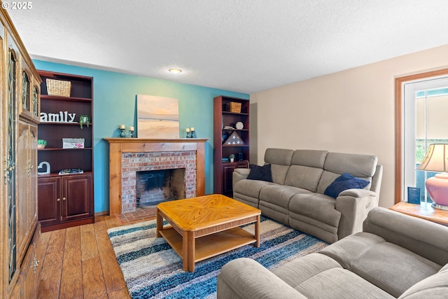 living room with a brick fireplace, a textured ceiling, and light wood-style floors