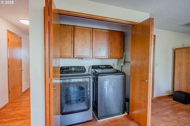 laundry area featuring visible vents, light wood-style flooring, cabinet space, a textured ceiling, and washer and dryer